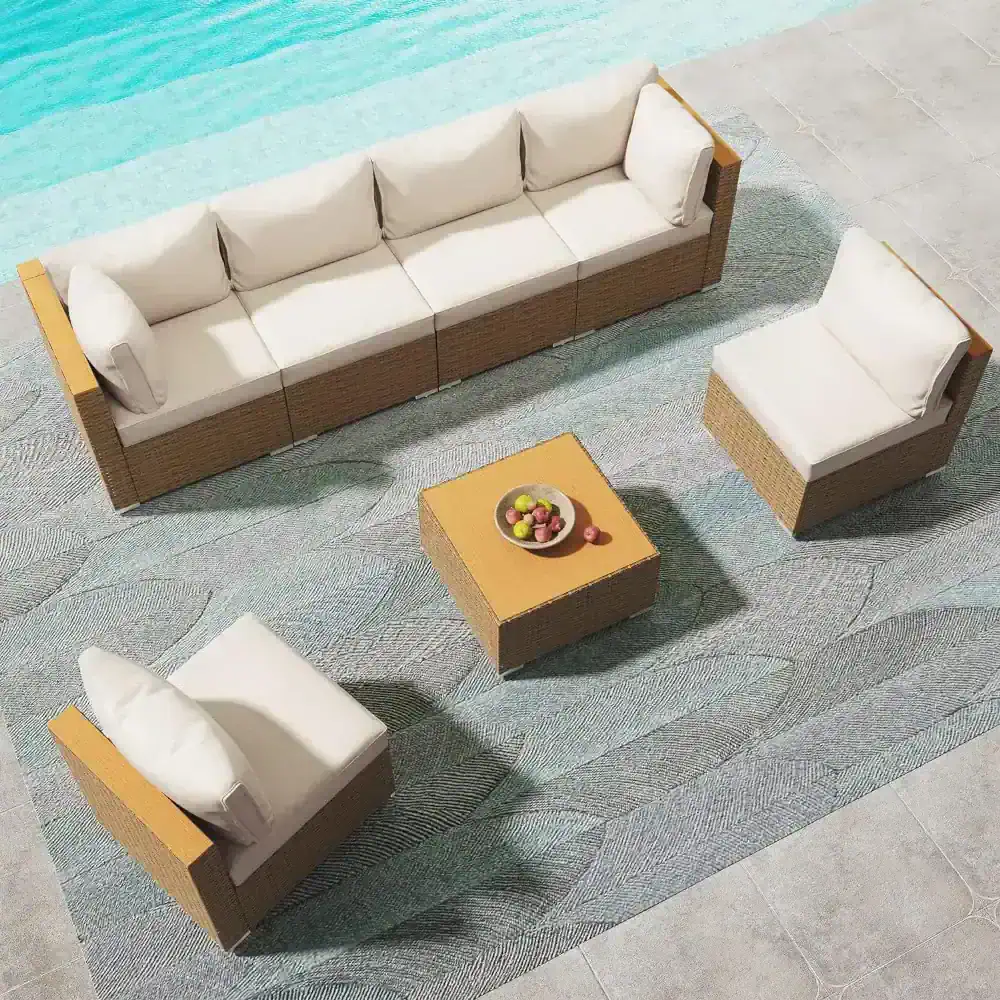 Elegant outdoor furniture set featuring a spacious wicker sofa and armchairs with plush white cushions, perfect for relaxing by the poolside or patio.