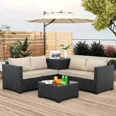 Stylish outdoor wicker furniture set with beige cushions, perfect for lounging on a patio or balcony with greenery and a large umbrella for shade.