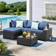 Luxury outdoor patio furniture set with navy cushions and floral pillows, perfect for relaxing by the poolside on a sunny day.