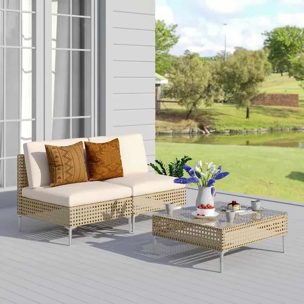 Stylish outdoor seating area with wicker sofa and coffee table, perfect for garden relaxation and outdoor living. Featuring comfortable cushions and fresh flowers for a cozy, inviting atmosphere.
