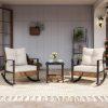 Stylish outdoor seating area with rocking chairs, cozy cushions, and a coffee table, perfect for relaxing and enjoying spring or summer days in a home or garden setting.