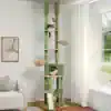 A tall green and beige multi-level cat tree with two cats lounging, located in a bright, modern living room near a large window. Perfect for indoor cats, offering play and relaxation.