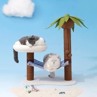 Cat lying on a white fluffy platform on a cat tree with a striped hammock, palm tree, and blue sky background.