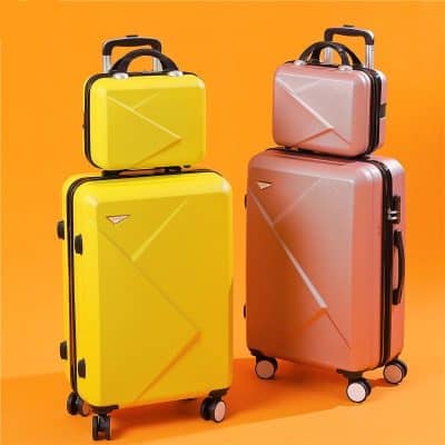 Yellow and pink hard-shell suitcases with wheels and handles against an orange background.