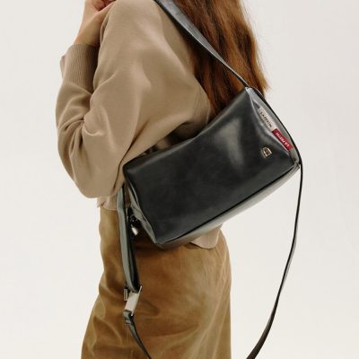 Premium black leather shoulder bag with adjustable strap, perfect for everyday use and stylish accessorizing. Features a sleek design with a small front logo and functional zip closure.