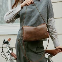 Handbag with shoulder strap hanging from woman's shoulder, stylish accessories for everyday fashion.