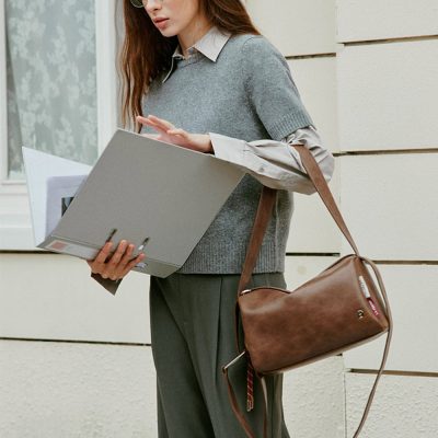 Stylish woman wearing glasses with a tan leather handbag from Monalisa Store, holding a folder, showcasing trendy eyewear and accessories for women. Perfect for fashion-conscious shoppers.