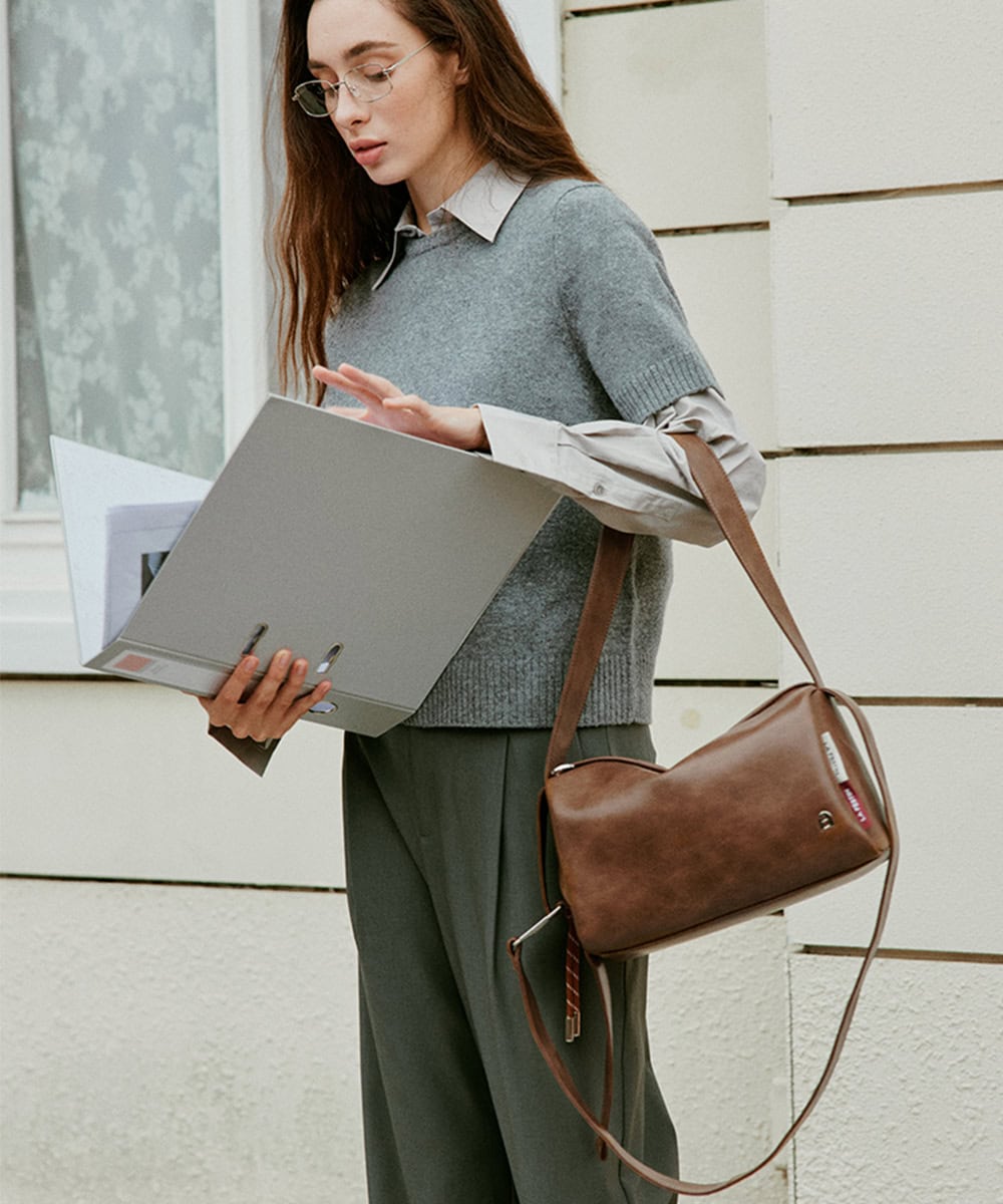 Stylish woman wearing glasses with a tan leather handbag from Monalisa Store, holding a folder, showcasing trendy eyewear and accessories for women. Perfect for fashion-conscious shoppers.