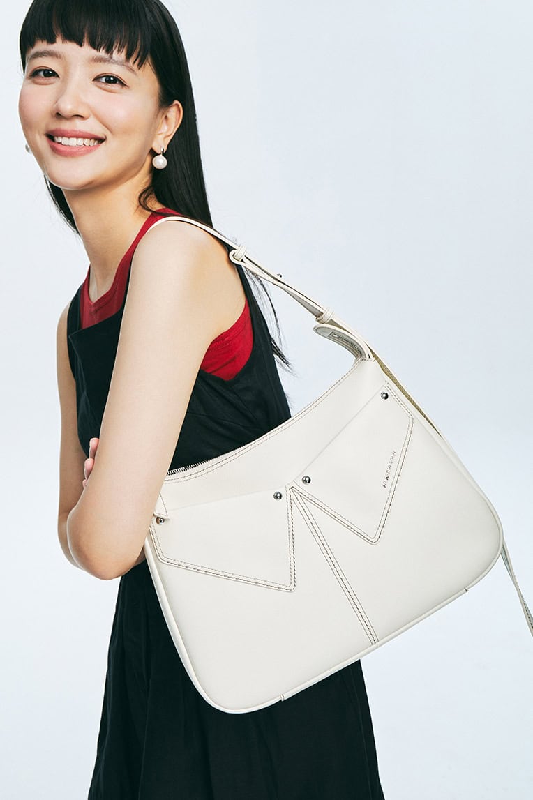 Elegant woman carrying a white designer handbag, showcasing luxury fashion accessories at Monalisa Store. Perfect for style-conscious shoppers and accessory enthusiasts.