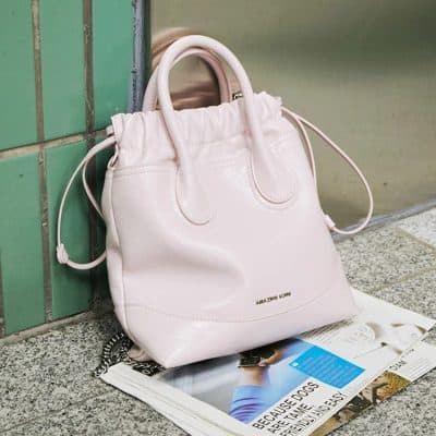 Luxury white designer handbag on green tiled wall with magazine, stylish fashion accessory.