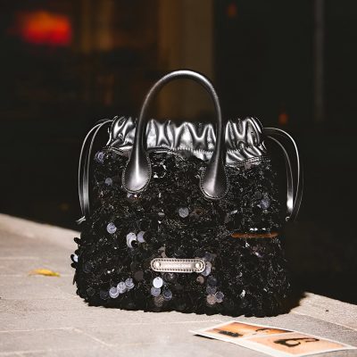 Black sequined fashion handbag with metallic handles and luxury branding, ideal for stylish accessories and high-end fashion statements.