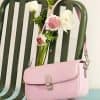 Pink handbag on green chair with fresh flowers, showcasing stylish accessories and floral decor, ideal for enhancing fashion statements and accessories collection.
