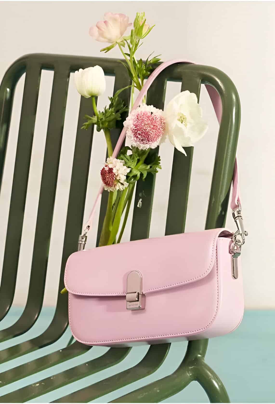 Pink handbag on green chair with fresh flowers, showcasing stylish accessories and floral decor, ideal for enhancing fashion statements and accessories collection.