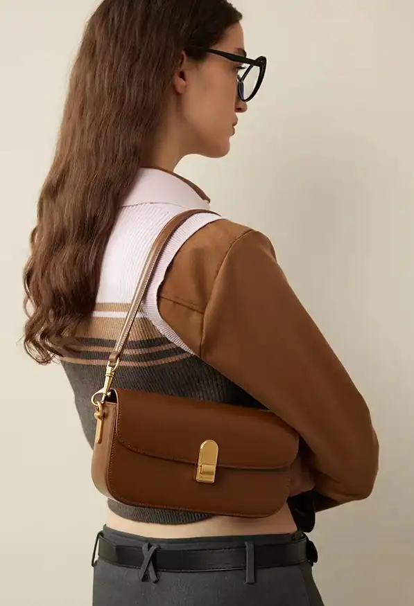 Brown leather handbag with gold hardware for women's fashion and accessories.