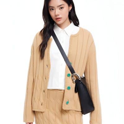Stylish young woman wearing a beige button-up cardigan, white shirt, and carrying a black shoulder bag, showcasing casual yet chic fashion from Monalisa Store.