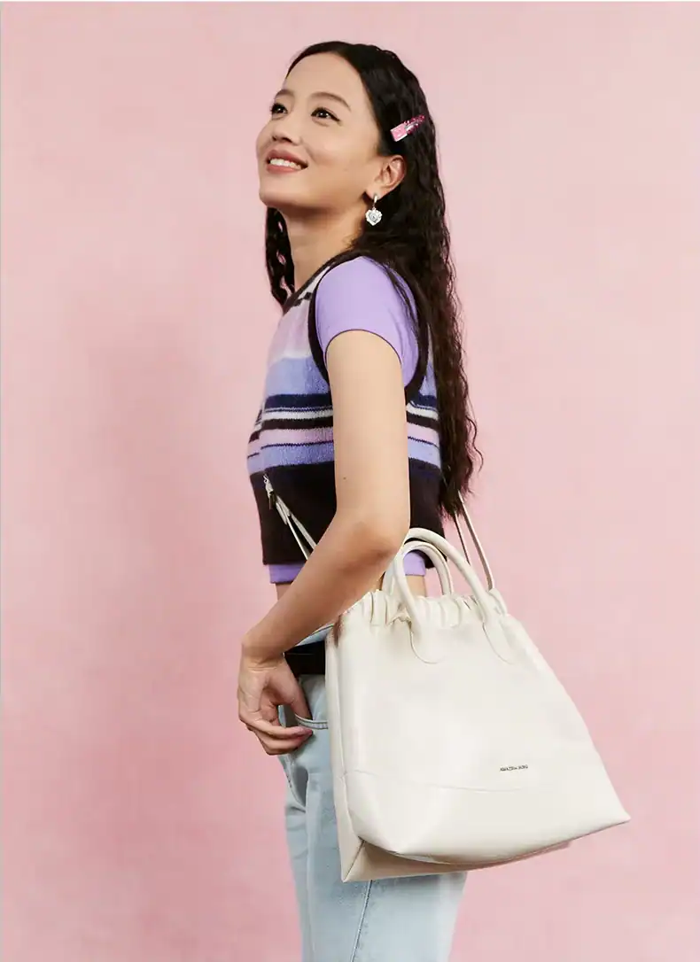 Elegant woman carrying a stylish white handbag, featuring the Monalisa Store logo, with a pink background and casual trendy outfit, showcasing luxury accessories for optical fashion.