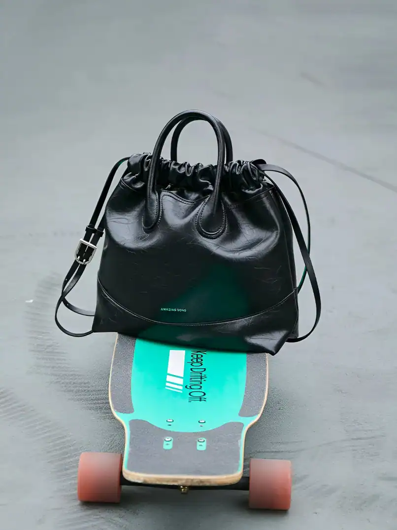 Stylish black leather handbag placed on a skateboard with a turquoise grip tape at Monalisa Medical Store, showcasing fashionable accessories and essential items for modern lifestyles.