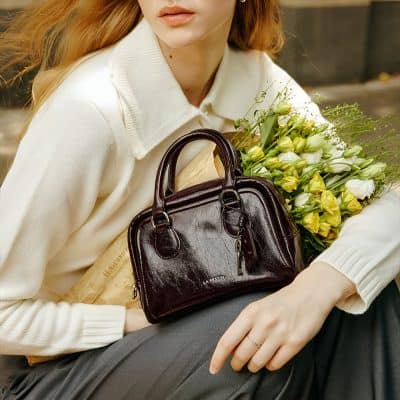 Black leather handbag with floral bouquet, stylish accessory for women.
