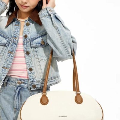 Stylish teenager wearing pink headphones and denim jacket holding a white and brown designer handbag, perfect for trendy fashion accessories.
