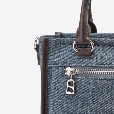 Stylish denim handbag with leather accents, sturdy top handle, and convenient zipper pocket for essentials, perfect for fashion-conscious women.