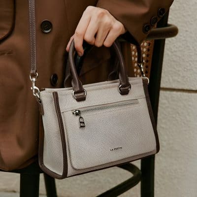 Water-resistant beige laptop bag with brown leather handles and accents, suitable for office and travel, stylish and functional accessory for professionals; ideal for carrying essentials in a chic manner.
