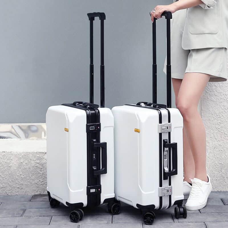 Roller luggage with telescopic handle on a city sidewalk, minimalist style, white color, travel accessory, travel gear, modern travel luggage, Monalisa Medical Store.