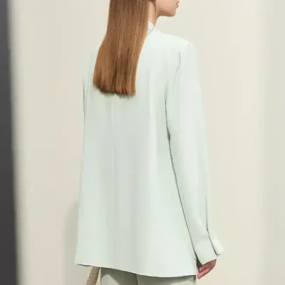 Elegant woman with straight auburn hair wearing a white blazer and wide-leg trousers, holding a textured handbag, showcasing sophisticated fashion and style for Monalisa Medical Store.