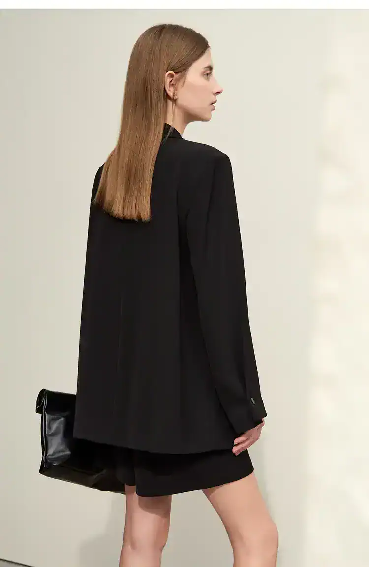 Elegant woman in black blazer and skirt with a stylish bag, showcasing modern fashion accessories at Monalisa Store for sophisticated eyewear and optical solutions.