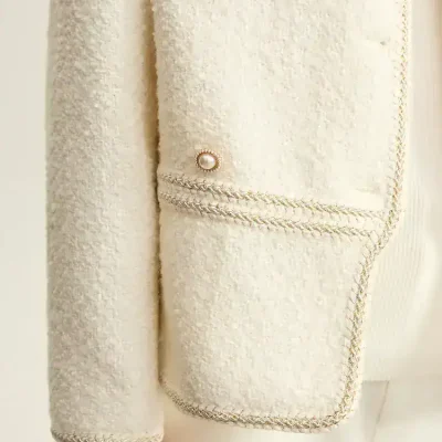 Luxurious cream-colored tweed blazer with elegant pearl button details, perfect for sophisticated fashion statements and upscale occasions.