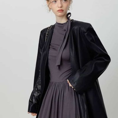 Elegant woman in black leather jacket and grey dress, fashion model showcasing luxury clothing at Monalisa Store, premium apparel for stylish women.