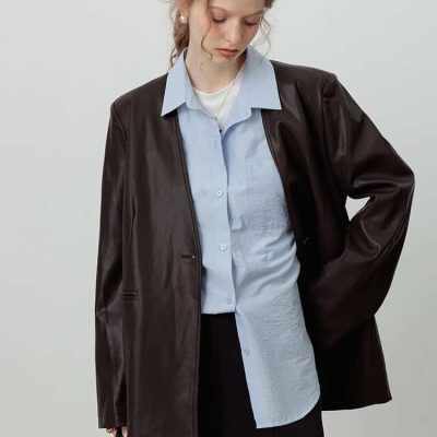 Stylish young woman with a leather jacket, blue shirt, and black skirt, holding a handbag, showcasing modern fashion at Monalisa Store for trendy optical accessories and eyewear.