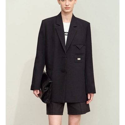 Black tailored blazer with unique pocket design and matching shorts, styled with knee-high black boots and a black clutch bag, showcasing modern fashion for women interested in chic, sophisticated clothing.