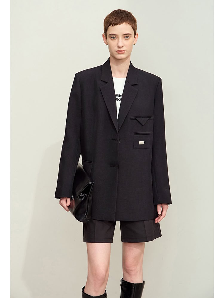 Black tailored blazer with unique pocket design and matching shorts, styled with knee-high black boots and a black clutch bag, showcasing modern fashion for women interested in chic, sophisticated clothing.