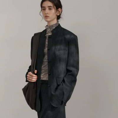 Elegant woman in a dark denim blazer and matching trousers, carrying a backpack, showcasing stylish and professional fashion suitable for work or casual outings.