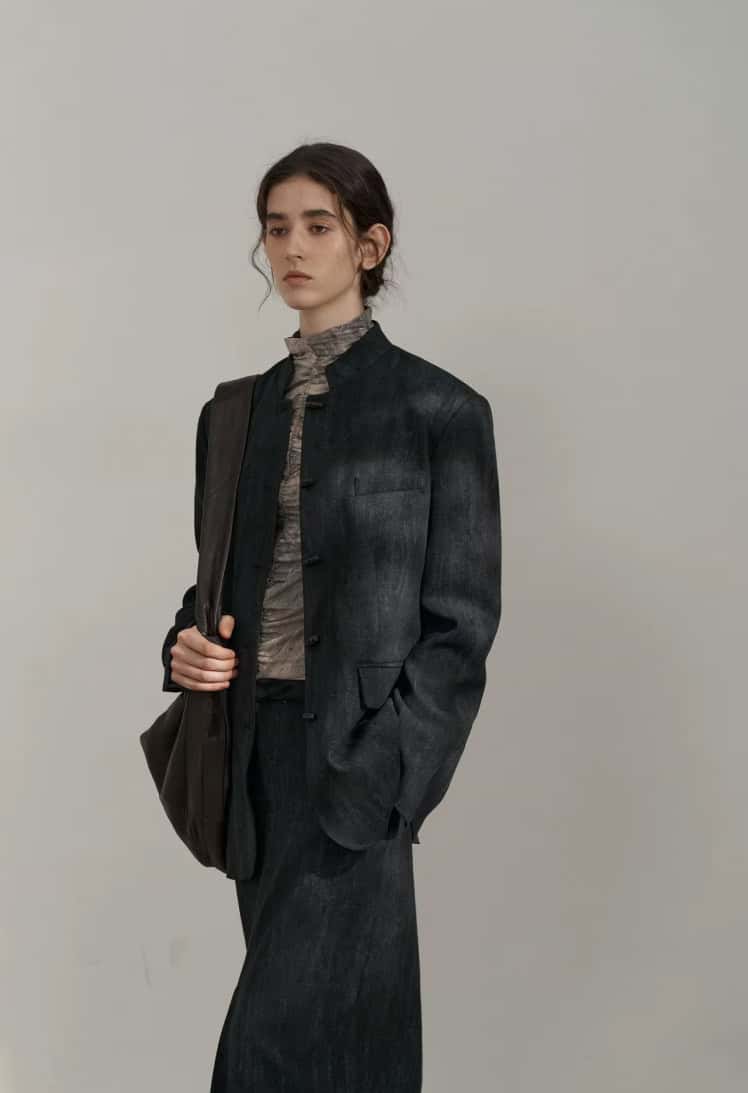 Elegant woman in a dark denim blazer and matching trousers, carrying a backpack, showcasing stylish and professional fashion suitable for work or casual outings.