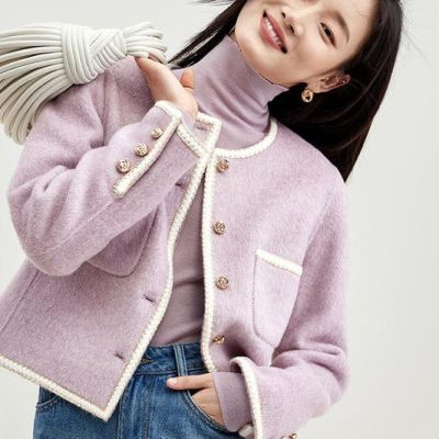Elegant woman in pastel pink blazer with pearl trim, casual jeans, and turtleneck sweater, showcasing stylish fashion for women.