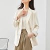 Elegant woman in white blazer and beige trousers, showcasing professional fashion styled for work or office wear. Perfect for office outfits, business casual looks, and elegant professional attire.