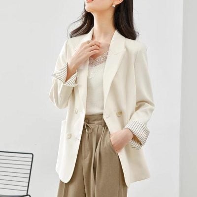 Elegant woman in white blazer and beige trousers, showcasing professional fashion styled for work or office wear. Perfect for office outfits, business casual looks, and elegant professional attire.