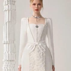 Elegant white bridal dress with floral embroidery and bow detail, perfect for wedding or special occasions. Designed for a sophisticated bridal look with lace accents.