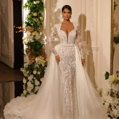 Elegant wedding gown with intricate lace and beadwork, featuring a deep neckline and long sheer sleeves, perfect for bridal fashion from Monalisa Store.