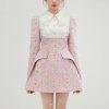 Luxurious pastel pink tweed dress with embroidered floral details, structured design, and playful hemline, perfect for elegant occasions and fashion-forward styling.