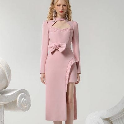 Elegant pink evening dress with lace details, floral bow accent, and thigh-high slit for a stylish look at formal events. Perfect for fashion-forward women seeking luxury and sophistication.