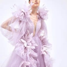 Elegant fashion model wearing a pastel pink tulle dress with floral and butterfly embellishments, showcasing Monalisa Store's high-end designer clothing collection and accessories for modern, stylish women.