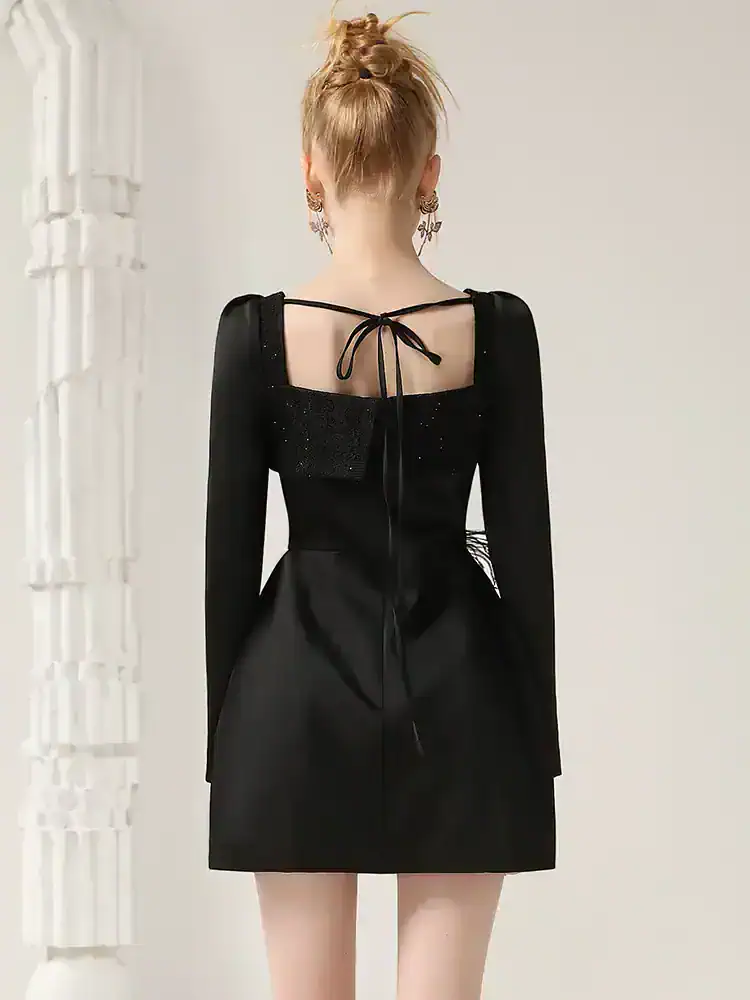 Elegant black dress with unique back detailing, perfect for fashionable occasions or stylish events. Features long sleeves, subtle shimmer, and a flattering silhouette for a sophisticated look.