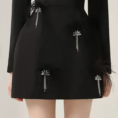 Elegant black mini skirt with jeweled flower embellishments and feather details, perfect for chic fashion statements.