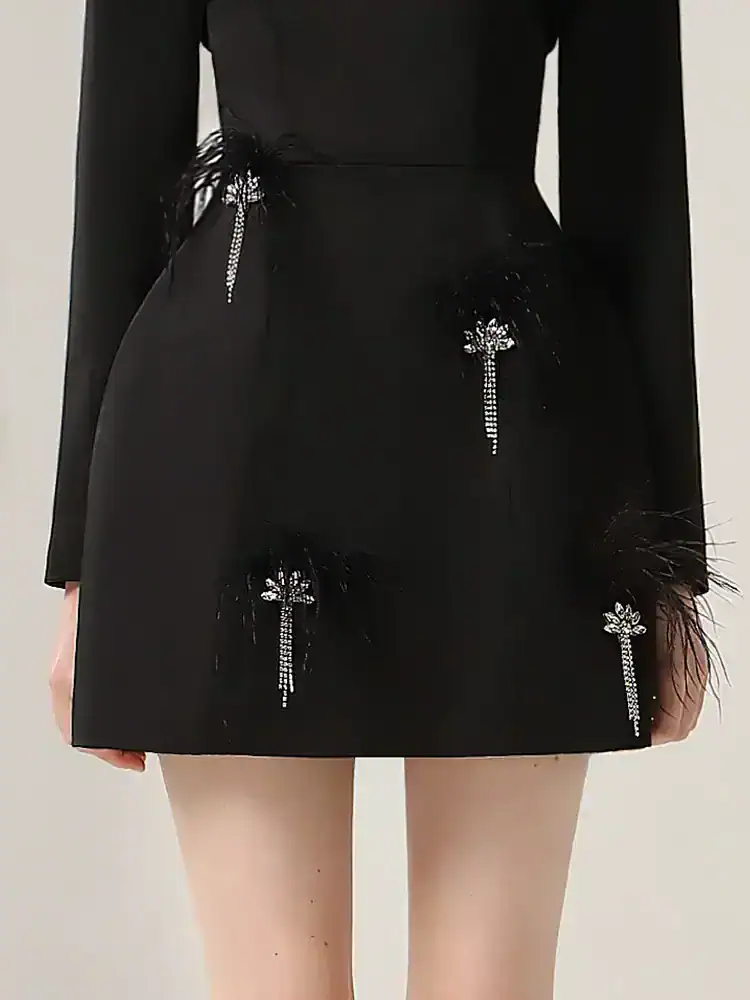Elegant black mini skirt with jeweled flower embellishments and feather details, perfect for chic fashion statements.