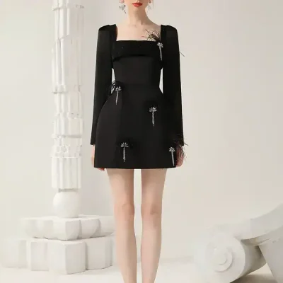 Elegant black mini dress with feather detailing and sparkling embellishments, perfect for fashion-forward occasions and stylish apparel shopping.