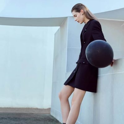 Black-haired woman in a black blazer and mini skirt holding a black sphere at Monalisa Medical Store.