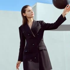 Black blazer dress fashion styling with a black ball, minimalistic outdoor setting. Perfect for modern, elegant women seeking sophisticated clothing and accessories.