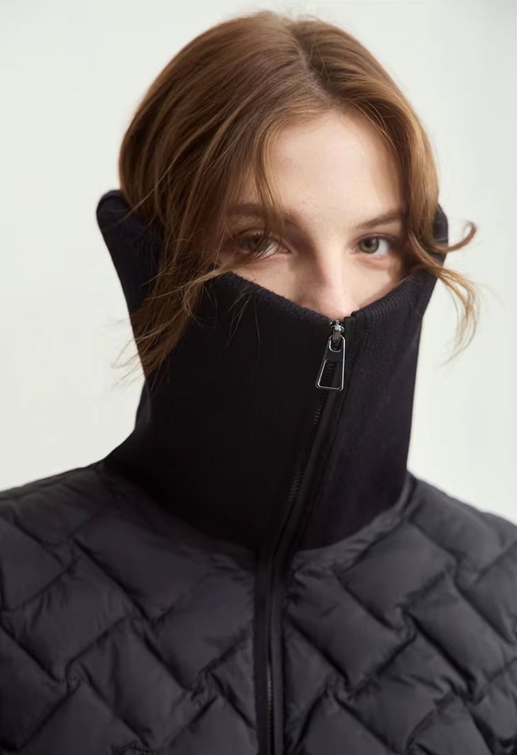 High-performance black quilted jacket with a zip-up neck warmer, ideal for outdoor winter activities, offering warmth and style, perfect for cold weather and outdoor sports.